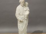 statue d'une femme tenant un enfant dans ses bras, posée sur un plancher en bois
