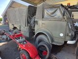a military truck parked in a garage with a lawn mower in front of it