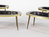 paire de tables d'appoint noires et dorées, avec des pieds dorés et un motif noir et blanc