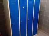 three blue lockers in a bathroom next to a toilet