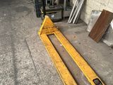 un chariot élévateur garé dans un garage, à côté d'un tas de bois