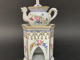 a close up of a white teapot with flowers on it