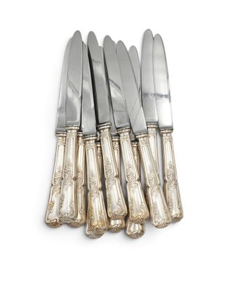 six silverplated knives and a knife holder on a white surface