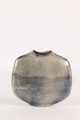 un vase noir et blanc posé sur une surface blanche
