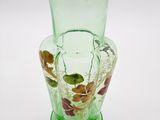 un vase en verre vert orné de feuilles, posé sur une surface blanche