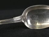 a silver spoon with a handle on a black surface