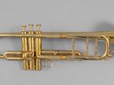 an antique brass trumpet with a brass bell on a gray background