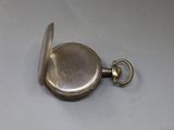 a silver pocket watch on a table with a chain
