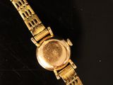 a close up of a gold wrist watch on a black surface