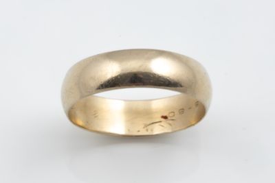 gros plan d'une bague en or sur une surface blanche