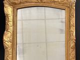 an ornate gold framed mirror on a black wall next to a window