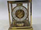 a gold clock sitting on a table with a white background