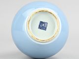 a blue and white vase with a gold rim sitting on a white surface