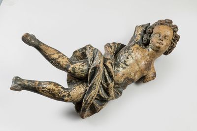 statue of a child laying on its back on a white surface