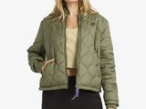 une femme vêtue d'une veste matelassée verte et d'un pantalon noir