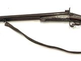 un vieux pistolet avec un canon en bois et une sangle, sur fond blanc