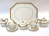 a white and gold tea set on a white table
