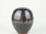 a black and brown vase sitting on a white surface