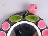 a pink bird sitting on top of a black and white mirror