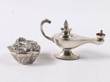 une petite théière en argent à côté d'une autre petite théière en argent