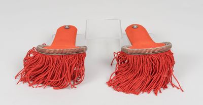 pair of orange tassels with fringes on a white surface