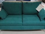 un canapé vert avec des coussins dessus, dans un magasin