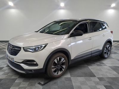 L'Opel blanche est garée dans une grande pièce au sol carrelé en damier.