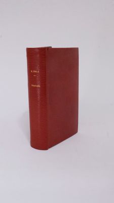 an old red book sitting on top of a white surface