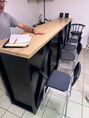un homme debout devant un comptoir, un livre à la main