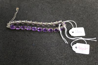 bracelet en perles de verre violettes avec une chaîne en argent et des pendentifs, sur un fond noir