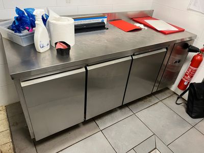 plan de travail en acier inoxydable dans une cuisine professionnelle, avec un extincteur