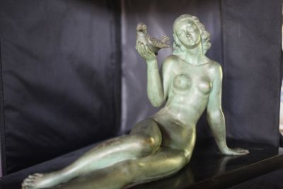 une statue en bronze représentant une femme assise sur une étagère
