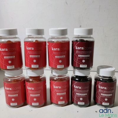 Plusieurs bocaux remplis d'un liquide rouge sont posés sur une surface blanche.