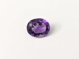 gros plan d'une pierre précieuse violette sur une surface blanche
