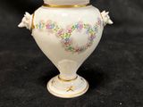 un vase blanc orné d'un motif floral sur fond noir