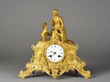une horloge en or sur laquelle figurent un homme et un chien