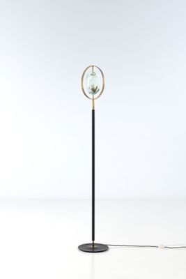 a black floor lamp with a glass globe on top of it