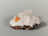 a small piece of rock with a piece of orange substance on top of it