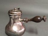 a silver teapot with a wooden handle on a table