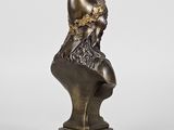 a bronze statue of a woman sitting on top of a bust