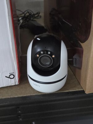 un petit appareil photo blanc posé sur une étagère, à côté d'une boîte
