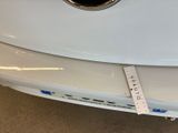 the rear end of a white car with a sticker on it ' s bumper