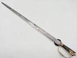 a close up of a knife on a white surface with a gold handle