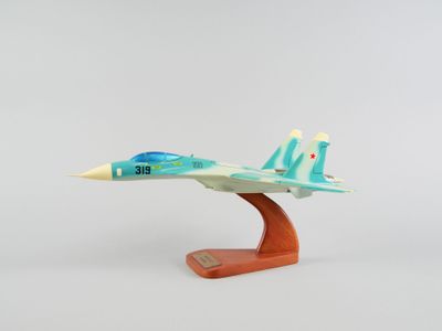 une petite maquette d'avion de chasse posée sur un socle en bois