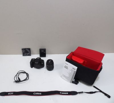 a camera, a lens, a camera case, and a camera strap on a white table