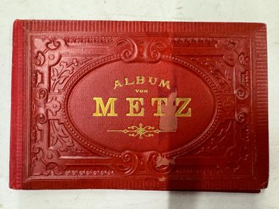 un vieil album rouge orné d'une inscription dorée, posé sur une table
