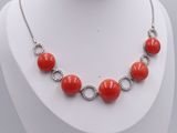 collier composé de perles de corail et de diamants, porté par un mannequin blanc