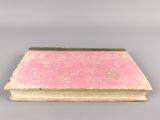 an old book with a pink cover sitting on top of a table