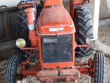 a red tractor that is parked in the dirt