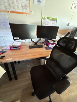 un bureau sur lequel sont posés deux écrans d'ordinateur, avec une chaise devant